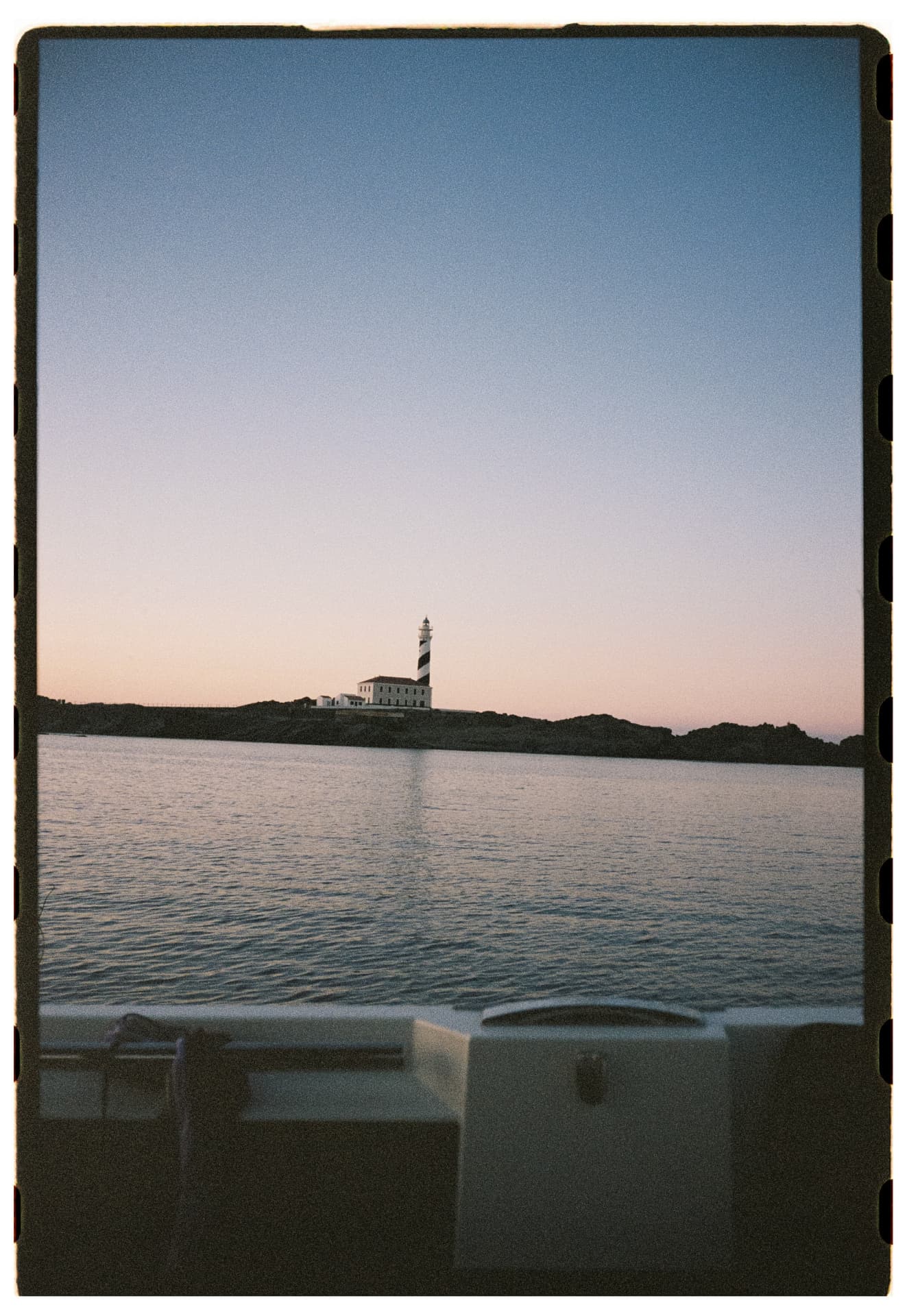 El faro de Favaritx al atardecer, desde el mar, en Menorca